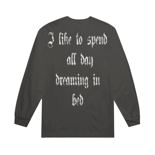 A dark gray unisex heavyweight long sleeve shirt from The Linda Lindas with gothic-style white text on the back that reads, “I like to spend all day dreaming in bed.”.
