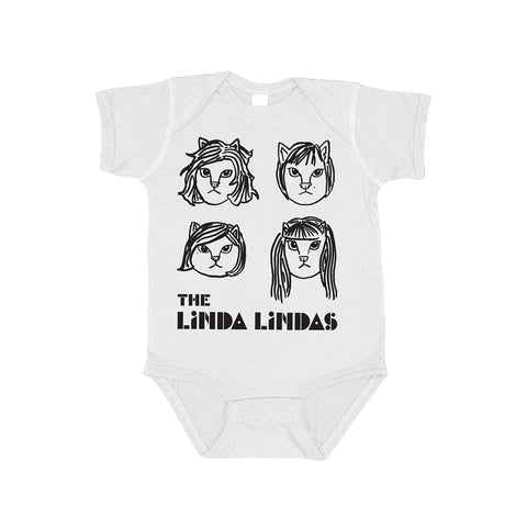 Image of a white onesie against a white background. The onesie features drawings of 4 different cat faces in black- three have shorter hair and one has longer hair. Below this in black text reads "the linda lindas".