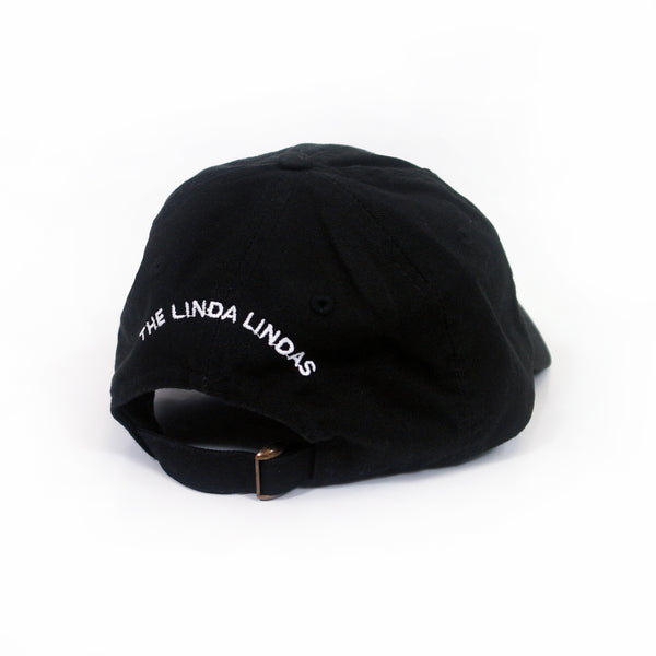 image of the back of a black dad hat on a white background. back of the hat  has white embroidery that says the linda lindas