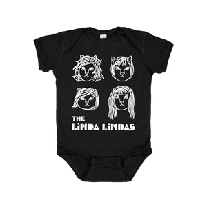 Image of a black baby onesie against a white background. The onesie features drawings of 4 different cat faces in white- three have shorter hair and one has longer hair. Below this in white text reads "the linda lindas".