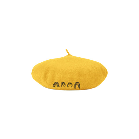 Image of a yellow beret hat against a white background. The hat features drawings of 4 different cat faces in white- three have shorter hair and one has longer hair. Below this in white text reads "the linda lindas". The cat faces are embroidered.